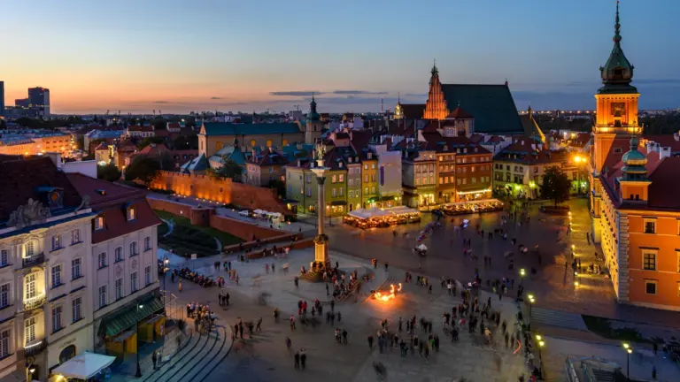 Panoramiczne ujęcie Zamku Królewskiego i warszawskiej Starówki o zachodzie słońca z lotu ptaka.